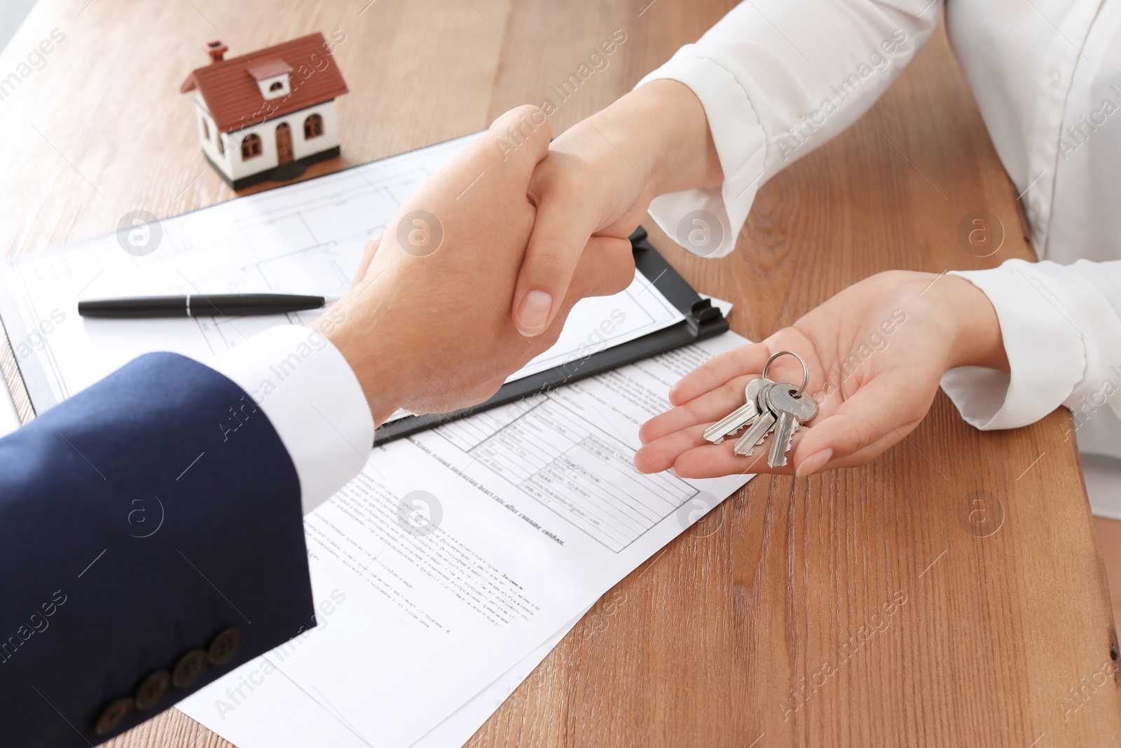 Photo of Woman shaking hands with real estate agent in office, closeup