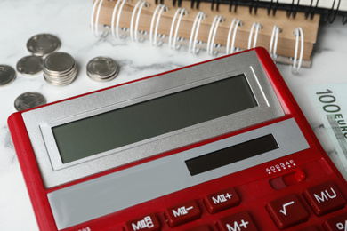 Photo of Calculator, money and notebooks on marble table, closeup. Tax accounting