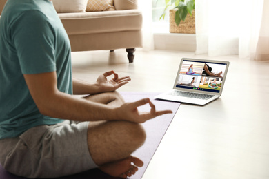 Image of Distance yoga course during coronavirus pandemic. Man having online video class via laptop at home, closeup