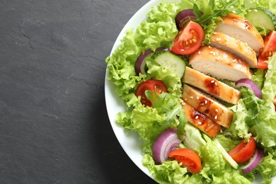 Photo of Delicious salad with chicken and vegetables on black table, top view. Space for text