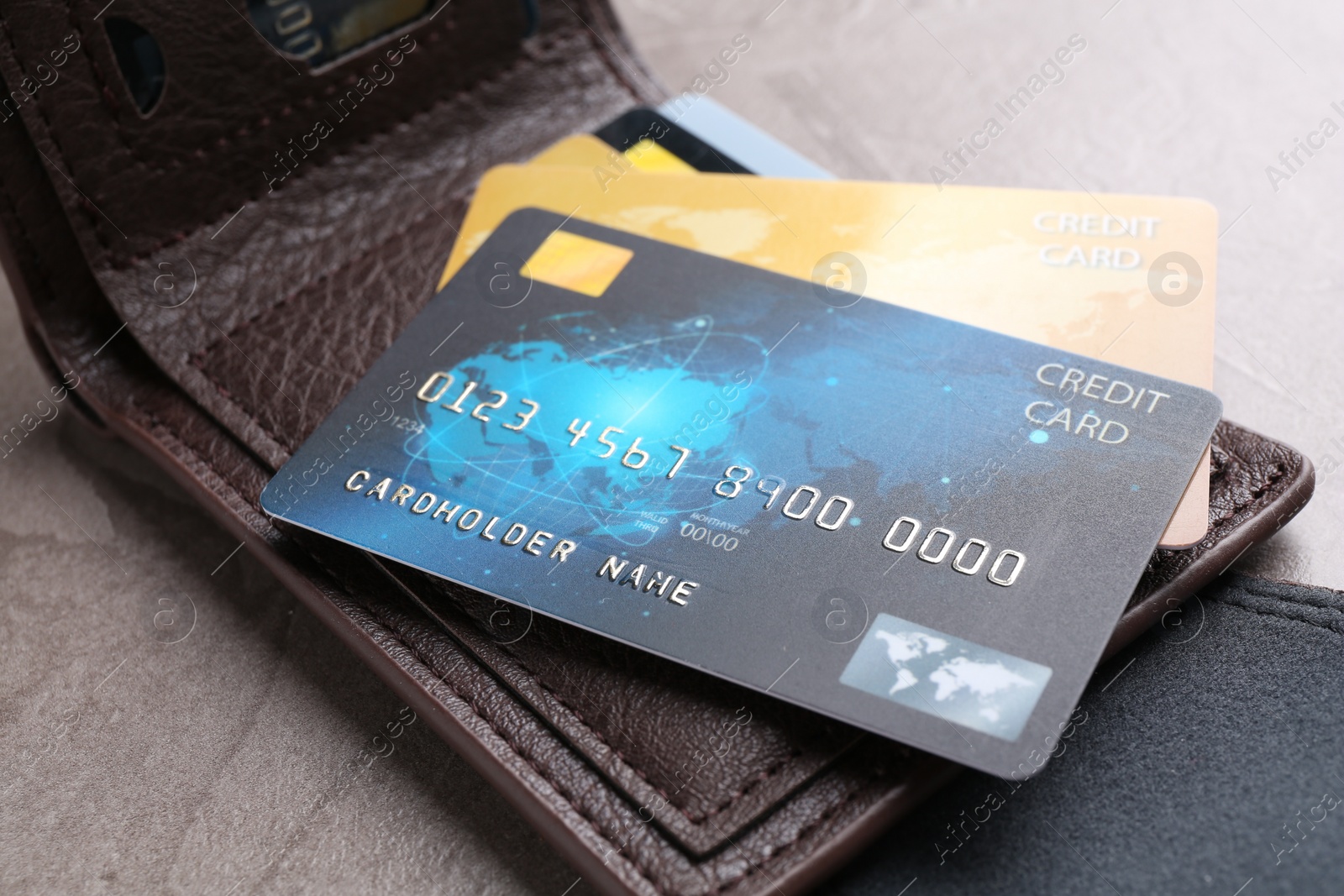 Photo of Credit cards and leather wallet on grey textured table, closeup