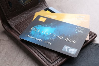 Credit cards and leather wallet on grey textured table, closeup