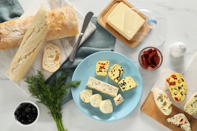 Photo of Different types of tasty butter served on white marble table, flat lay