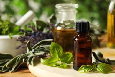 Photo of Different fresh herbs with oils on wooden table, closeup