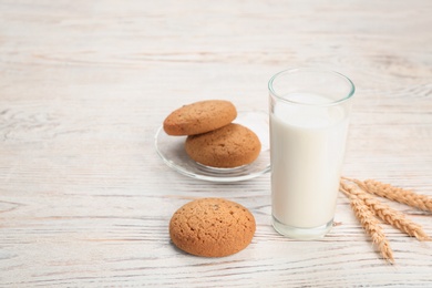 Glass of milk and oatmeal cookies on wooden table. Fresh dairy product