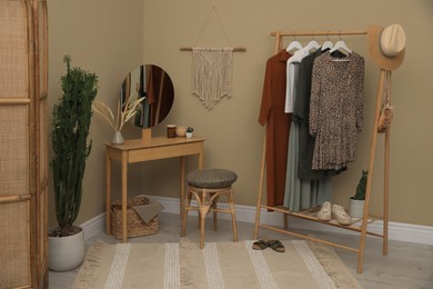 Photo of Modern dressing room interior with clothing rack, wooden table and mirror