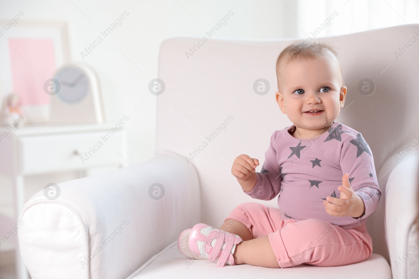 Photo of Cute baby girl sitting in armchair at home. Space for text
