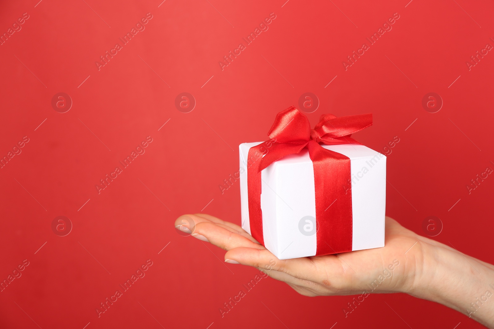 Photo of Woman holding gift box on red background, space for text. Valentine's Day celebration