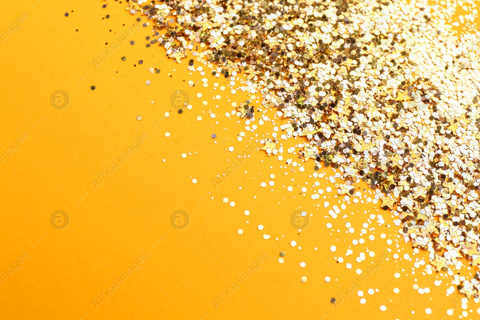 Photo of Shiny bright golden glitter on pale orange background. Space for text