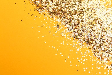 Shiny bright golden glitter on pale orange background. Space for text