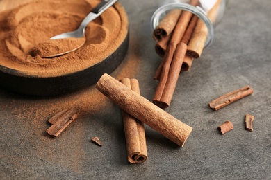 Aromatic cinnamon sticks and powder on grey background