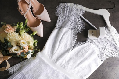 Flat lay composition with white wedding dress on grey stone table