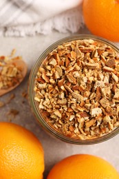 Jar of dried orange zest seasoning and fresh fruits on light grey table, flat lay
