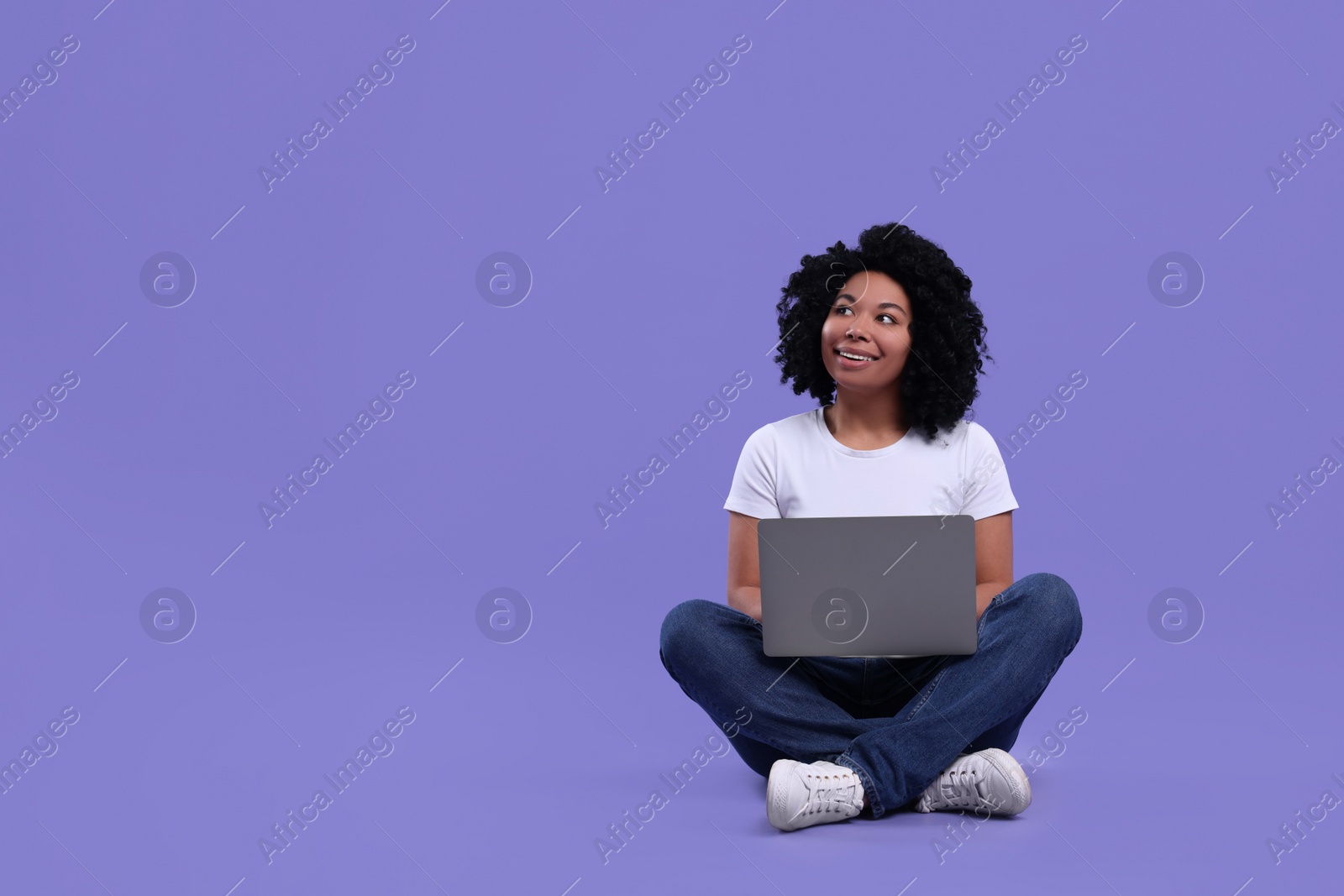 Photo of Happy young woman using laptop on purple background. Space for text
