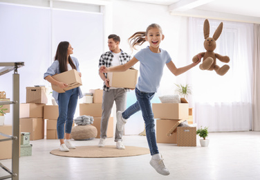 Happy family in room with cardboard boxes on moving day