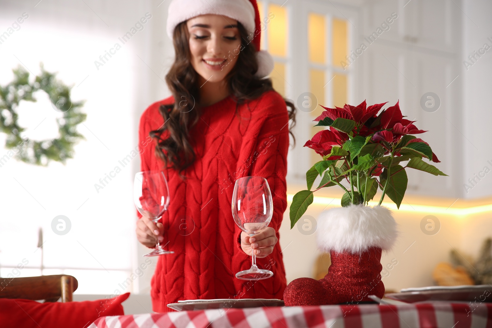 Photo of Young woman setting table for Christmas dinner in kitchen