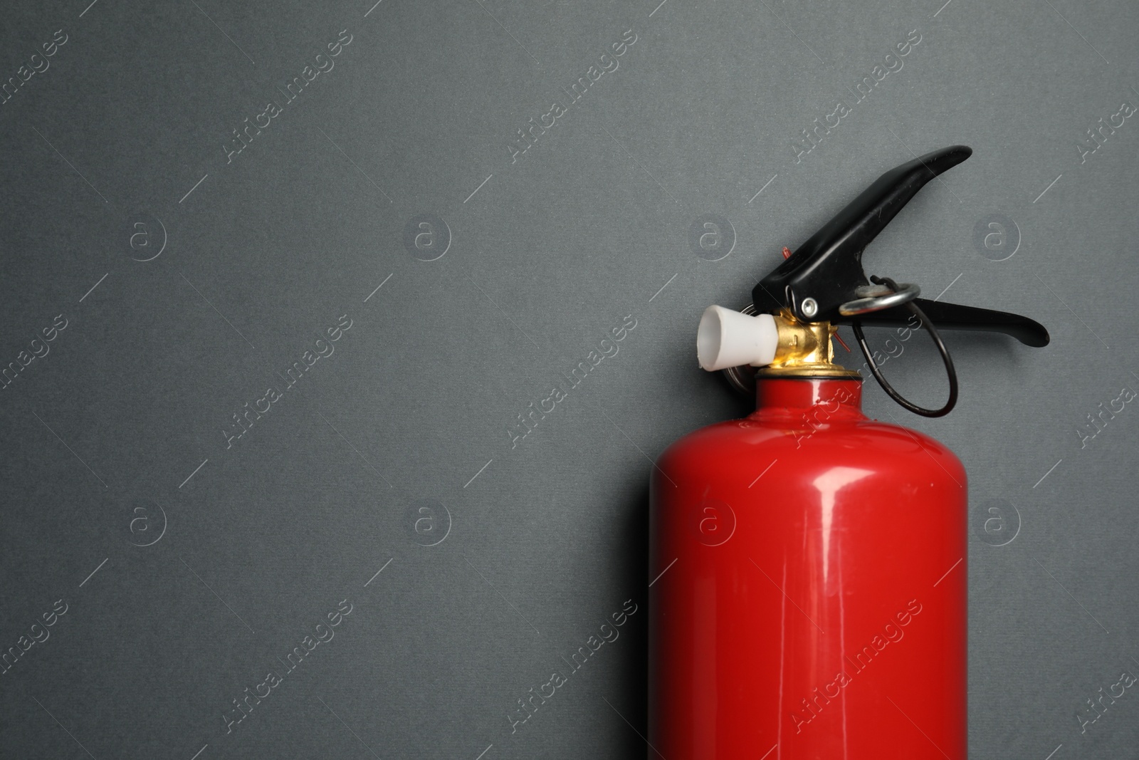 Photo of One red fire extinguisher on gray background, top view. Space for text