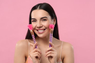 Photo of Happy woman with different makeup brushes on pink background. Space for text