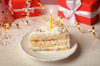 Photo of Slice of delicious birthday cake with candle on table