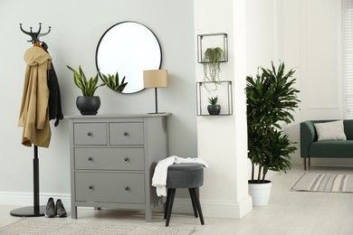 Hallway interior with stylish furniture, clothes rack and mirror