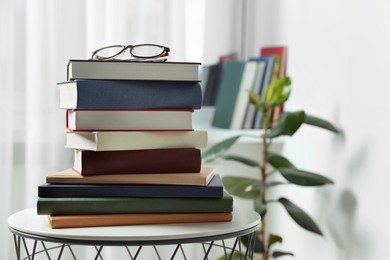 Photo of Stack of many different books and glasses on coffee table indoors. Space for text