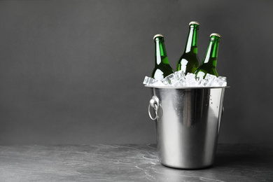 Photo of Metal bucket with beer and ice cubes on grey background. Space for text