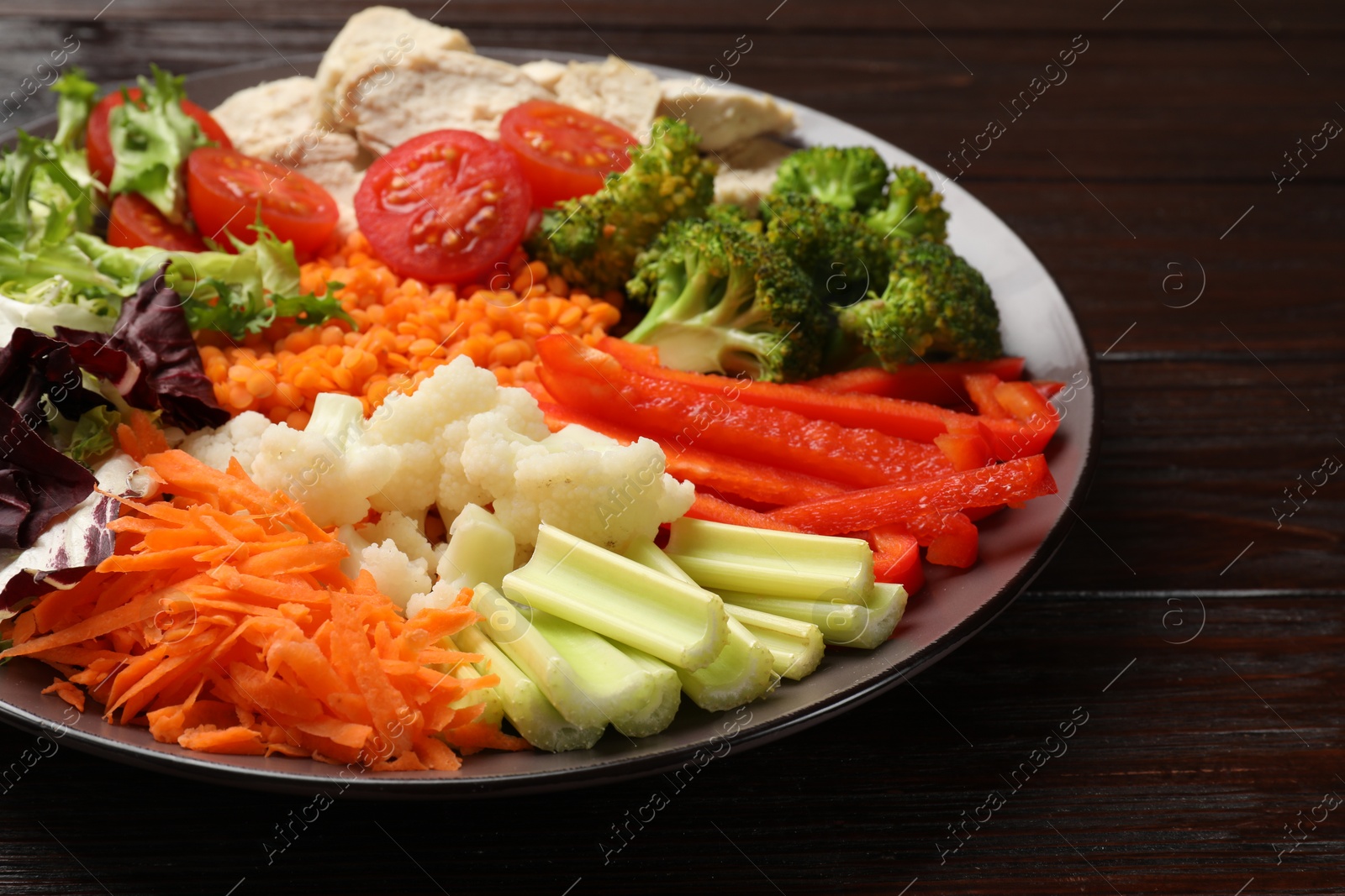 Photo of Balanced diet and healthy foods. Plate with different delicious products on dark wooden table, closeup