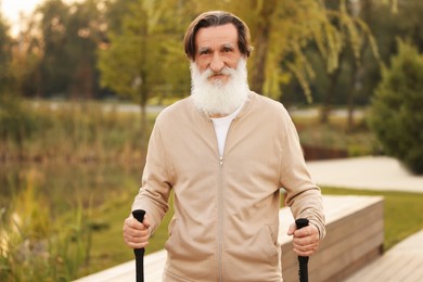 Photo of Senior man with Nordic walking poles outdoors