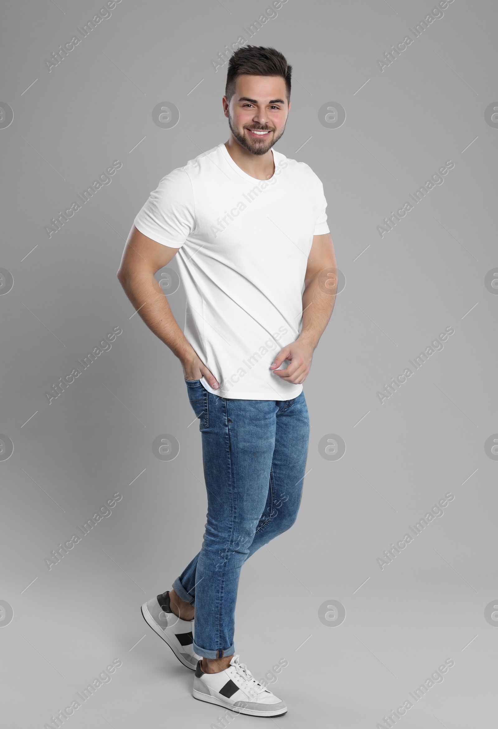 Photo of Young man in stylish jeans on grey background