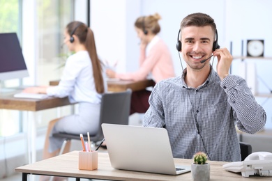 Male receptionist with headset at desk in office
