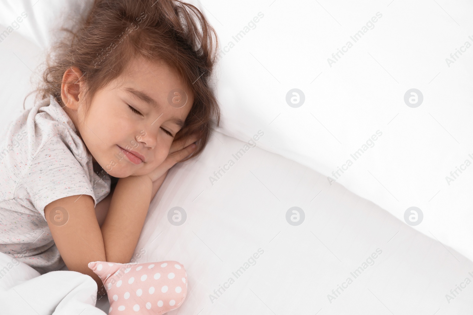 Photo of Cute little girl with toy sleeping in bed