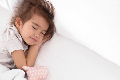Cute little girl with toy sleeping in bed