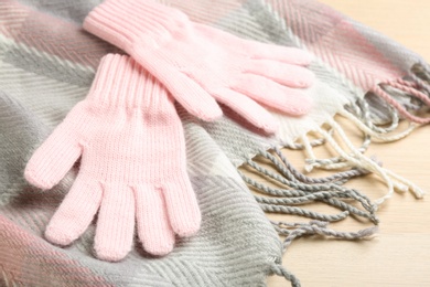 Photo of Stylish gloves and scarf on white wooden background, closeup