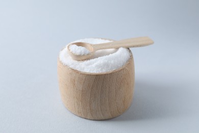 Photo of Organic white salt in bowl and spoon on light grey background, closeup