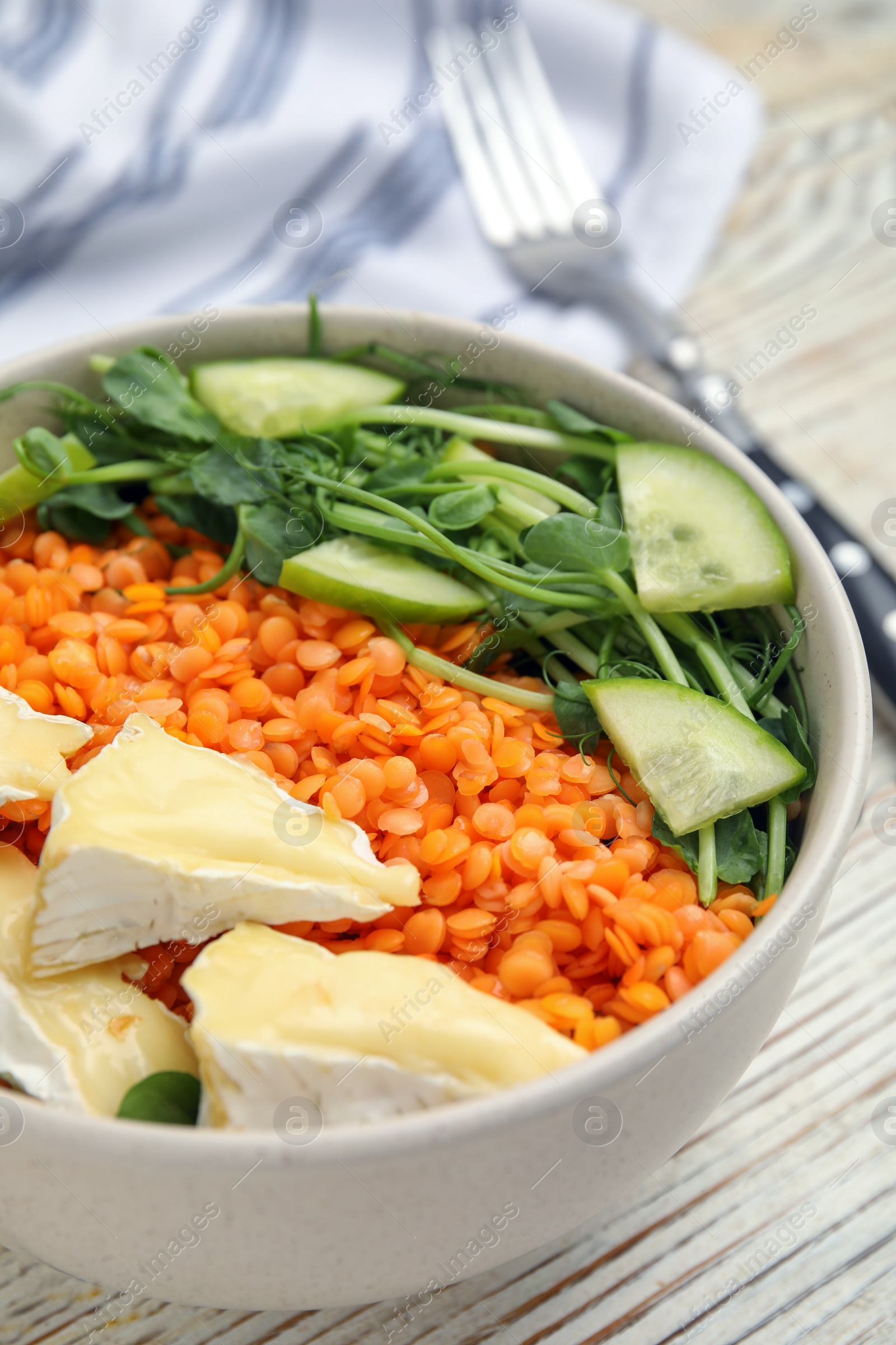 Photo of Delicious lentil bowl with soft cheese and cucumber on white wooden table