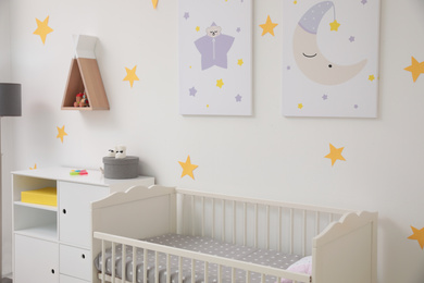 Photo of Stylish baby room interior with crib and decor elements