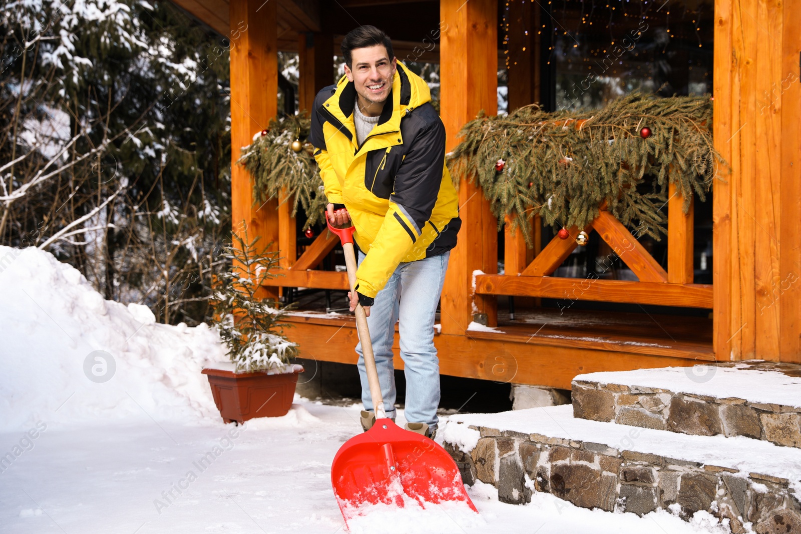 Photo of Man removing snow from house yard with shovel on winter day