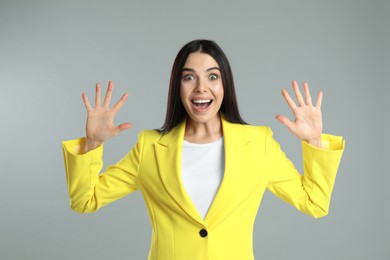 Photo of Woman showing number ten with her hands on grey background