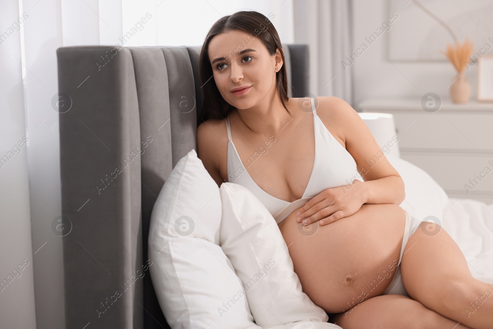 Photo of Beautiful pregnant woman in stylish comfortable underwear on bed at home