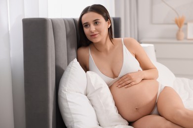 Photo of Beautiful pregnant woman in stylish comfortable underwear on bed at home