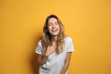 Photo of Cheerful young woman laughing on yellow background