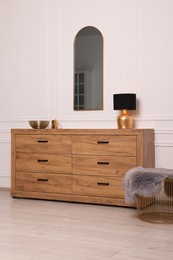 Photo of Stylish room interior with chest of drawers, mirror and decor elements