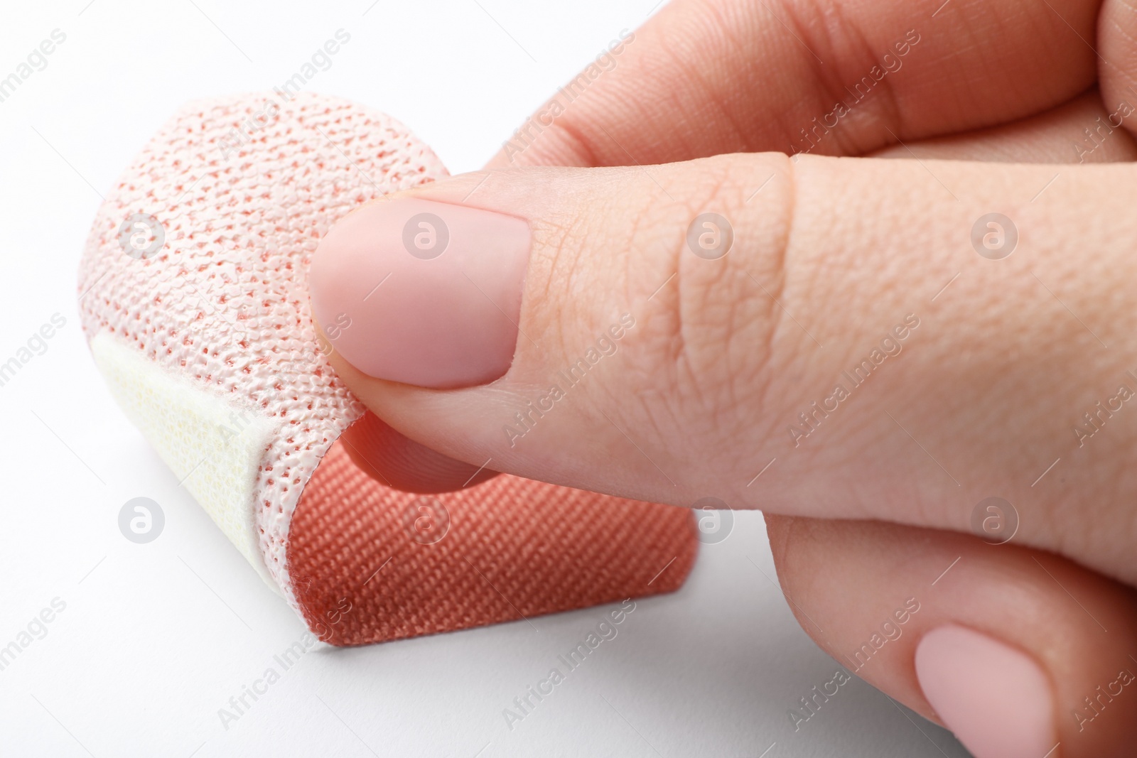 Woman putting sticking plaster on white background, closeup. First aid item Photo of Woman putting sticking plaster on white background, closeup. First aid item