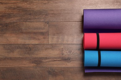 Photo of Bright rolled camping mats on wooden background, flat lay. Space for text