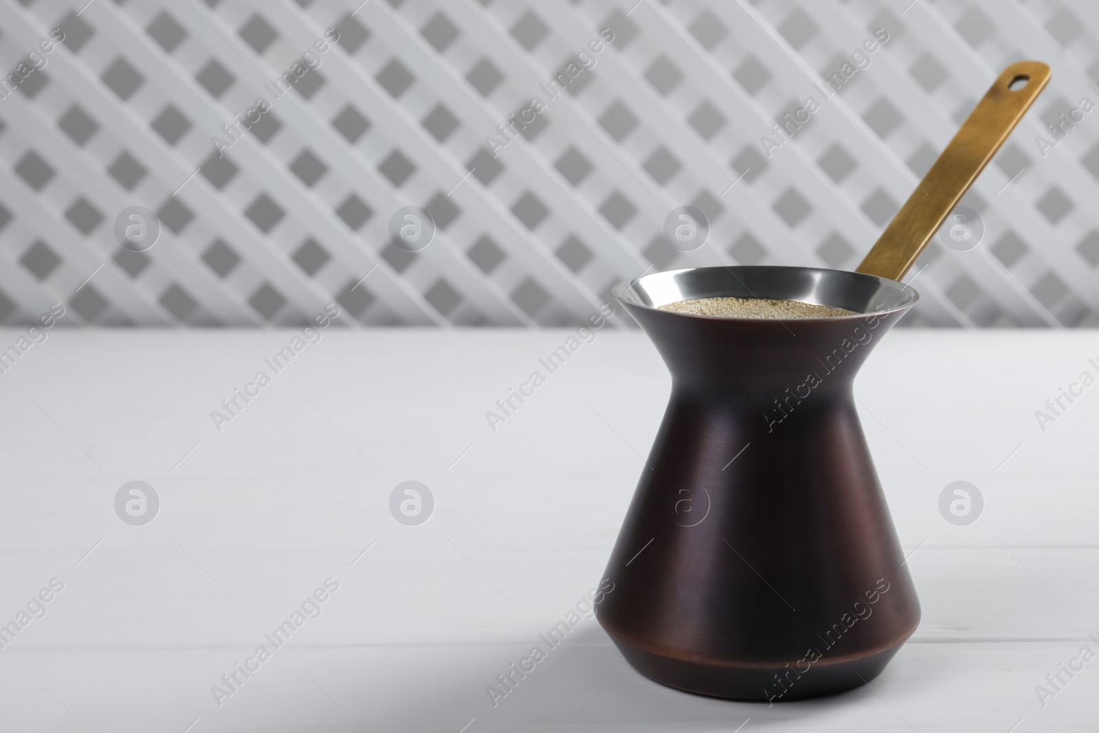Photo of Turkish coffee pot with hot drink on white wooden table, space for text