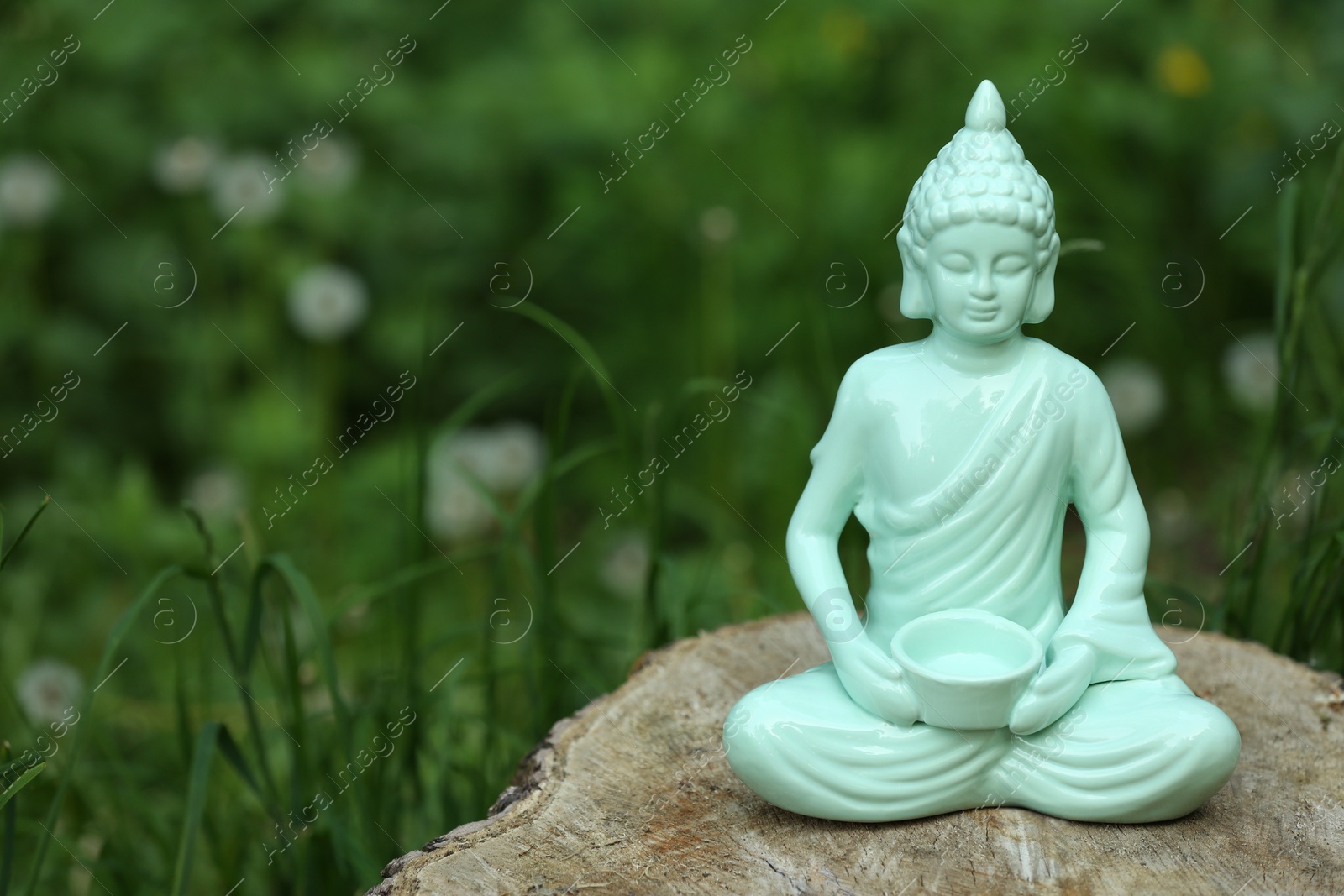 Photo of Decorative Buddha statue on stump outdoors, space for text