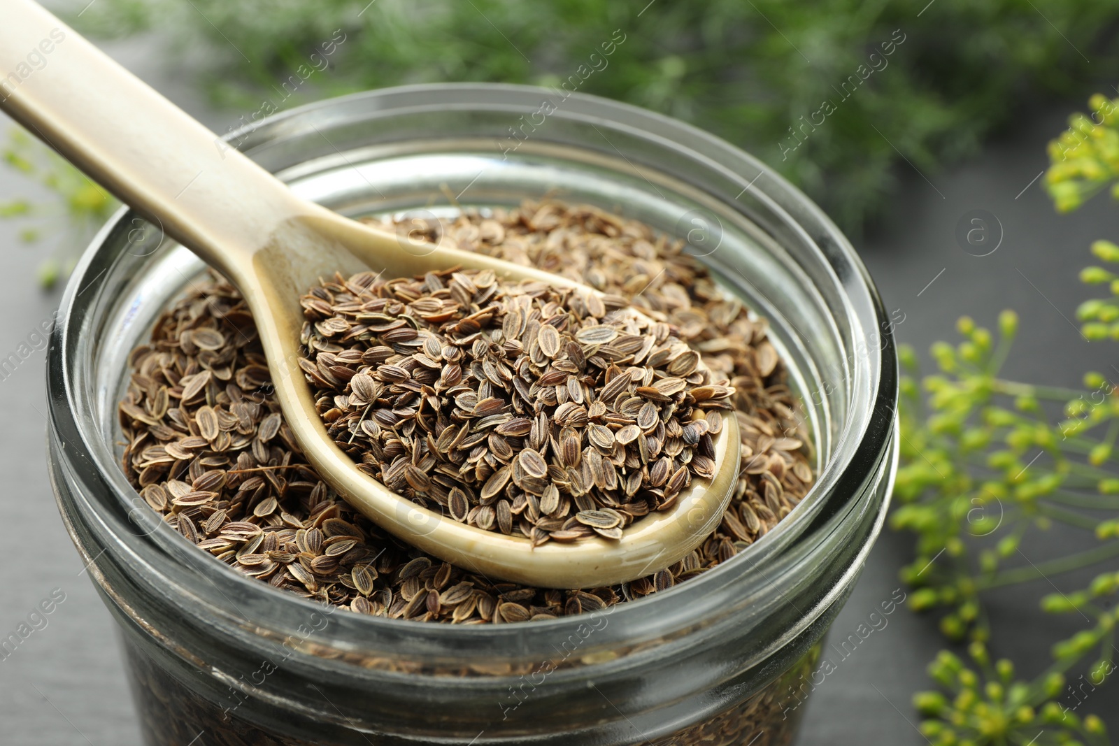 Photo of Jar with dry dill seeds and spoon on table, closeup