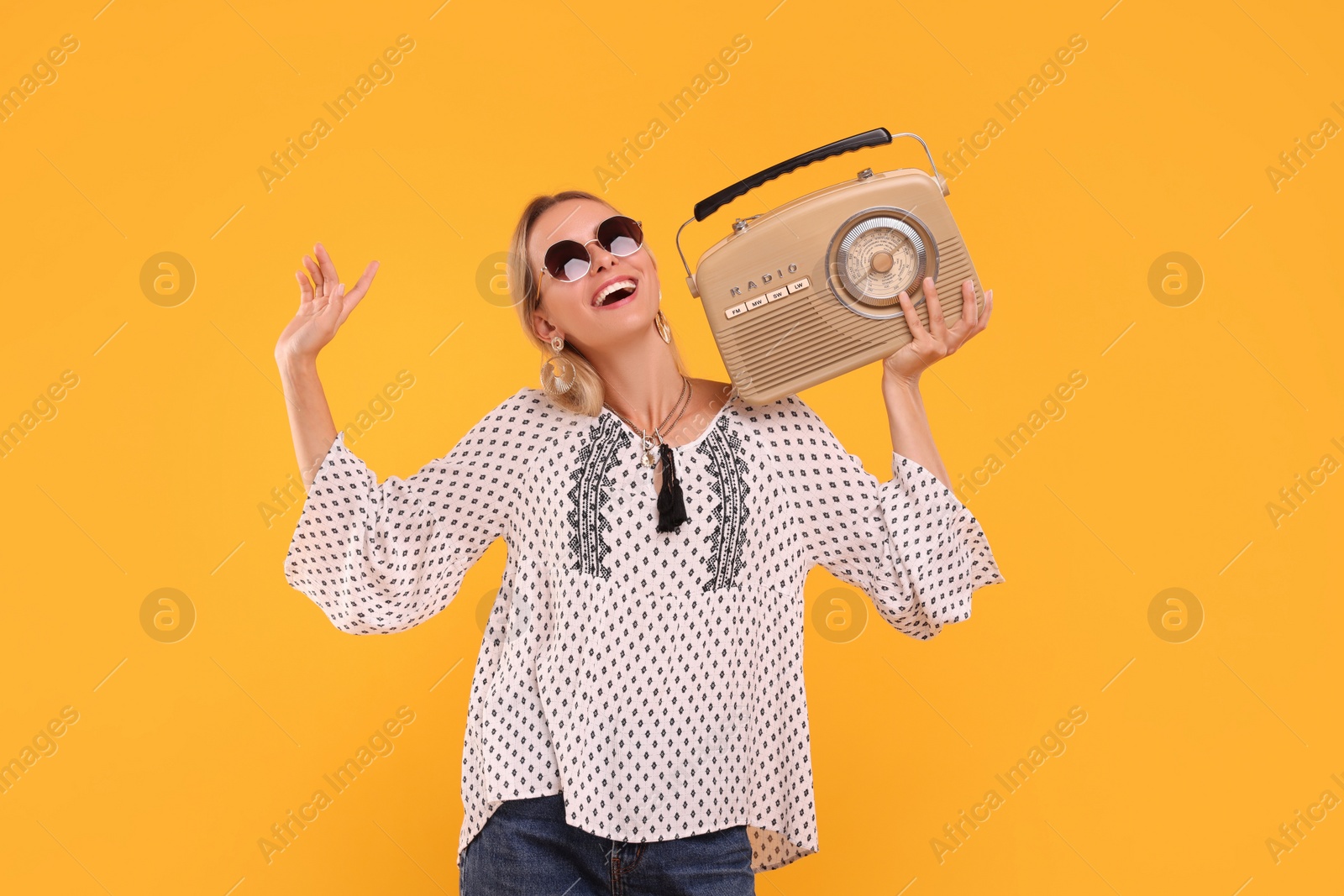 Photo of Portrait of happy hippie woman with retro radio receiver on yellow background