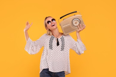 Portrait of happy hippie woman with retro radio receiver on yellow background