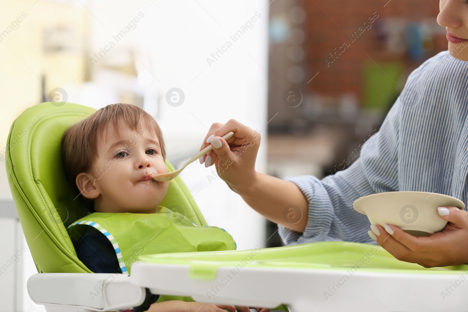 Photo of Young nanny feeding cute little baby at home